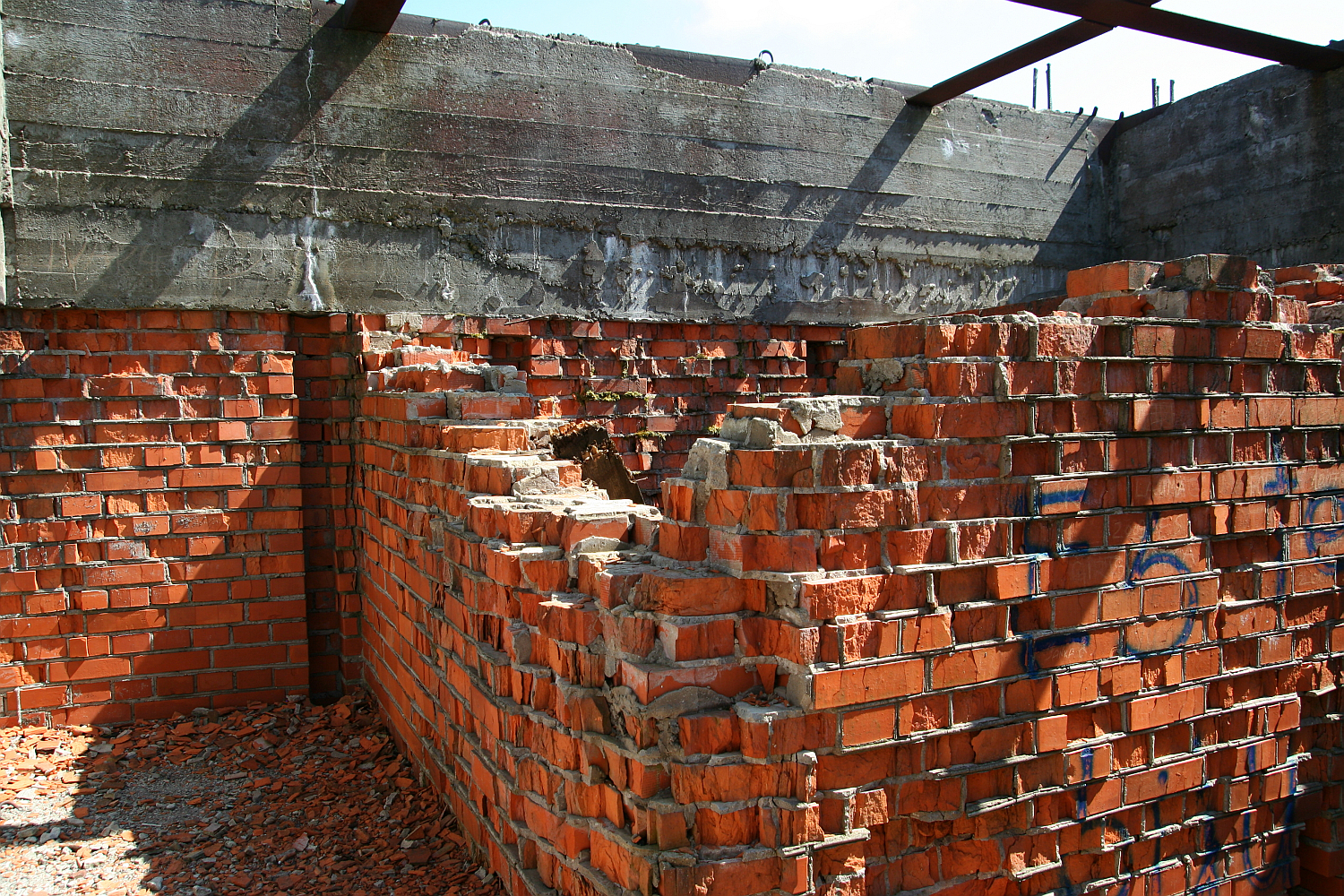 Unfinished and abandoned, the red brick structure stands in disrepair with a fragmented wall under a concrete ceiling on Gaiziņš, exposed to the elements and the relentless passage of time.