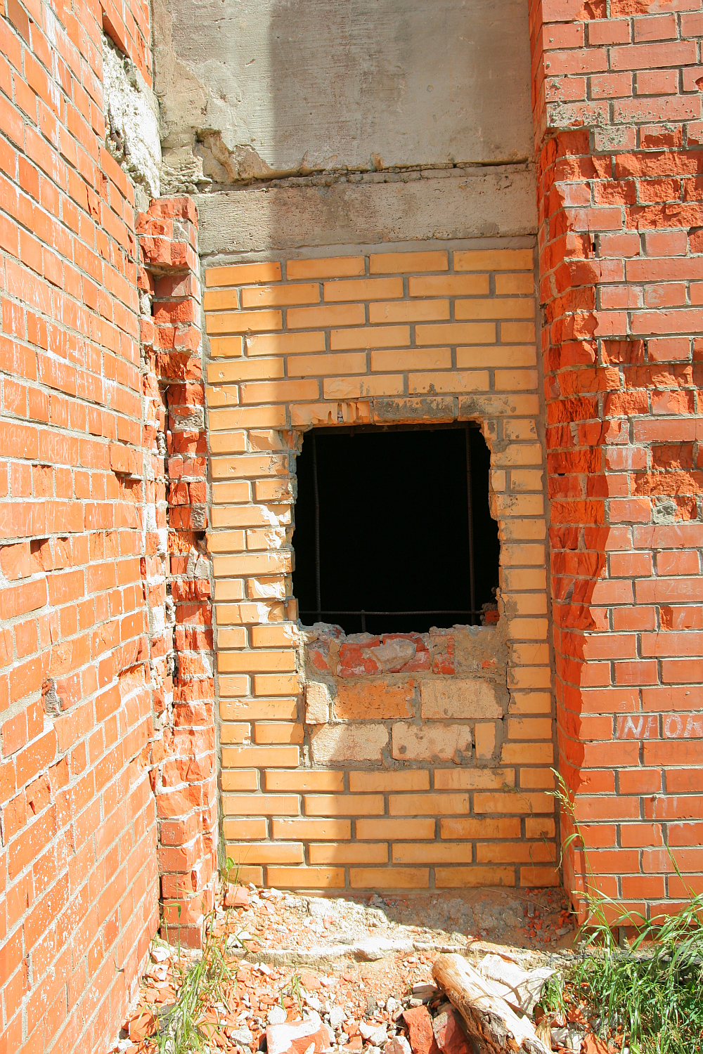 A wall with contrasting brickwork indicates a patched section around a square opening, hinting at repairs or alterations in an unfinished or dilapidated Gaiziņš building.