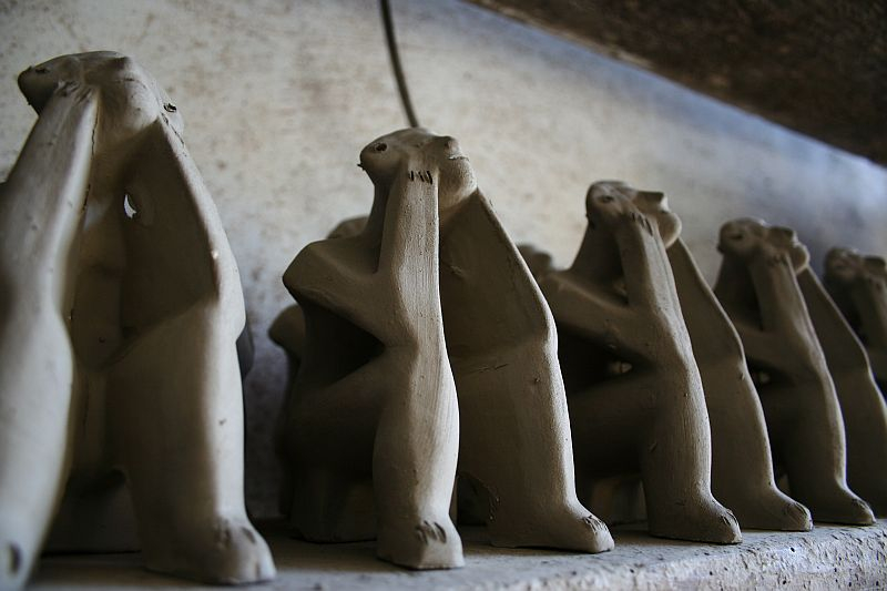 Row of stylized, elongated ceramic meerkat sculptures from Romania standing in a line, with a shallow depth of field focusing on the second from the left.