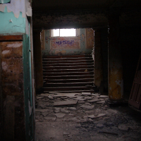 A Daugavgrīva staircase in an old building with a broken window.