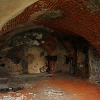 A room with a Daugavgrīva brick wall and a red floor.