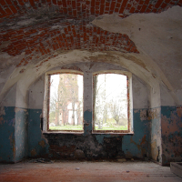 A room with a Daugavgrīva window overlooking a brick wall.