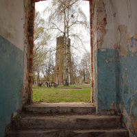 A doorway in the old Daugavgrīva building with a tower in the background.