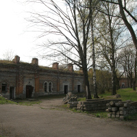 A Daugavgrīva brick building amidst a grassy field.