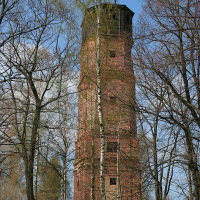 The Daugavgrīva water tower stands tall in the middle of a forest, showcasing its sturdy brick construction.