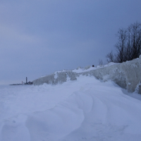 A frozen coastline with a lighthouse in Daugavgrīva during winter.