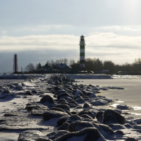 A frozen lake with a lighthouse in Daugavgrīva during winter.