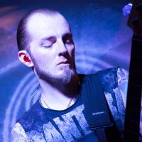 A man with a shaved head and goatee stands with eyes closed while playing an electric guitar, embodying the spirit of folk metal. His tattoos are visible on both arms as he wears a sleeveless shirt with partially visible text. The blue and purple lighting adds to the dramatic effect, reminiscent of an Eluveitie band performance.