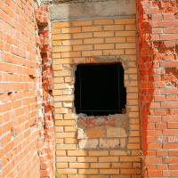 A wall with contrasting brickwork indicates a patched section around a square opening, hinting at repairs or alterations in an unfinished or dilapidated Gaiziņš building.