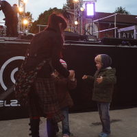 A woman and two children standing in front of a stage during the Dzelzs vilks ielīgo '09 event.
