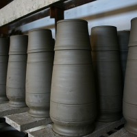 Freshly thrown clay pots lined up on a shelf in Romania, showcasing the uniformity and precision of a potter's craft before they are fired in the kiln.