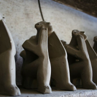 Row of stylized, elongated ceramic meerkat sculptures from Romania standing in a line, with a shallow depth of field focusing on the second from the left.