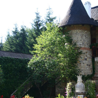 A quaint stone tower with a conical roof, reminiscent of Romania's countryside, is nestled amongst verdant trees and a vibrant garden of roses, creating a picturesque scene that exudes old-world charm.