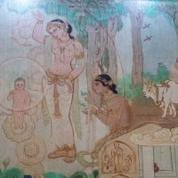 A detailed mural depicts a serene forest setting with several figures. A central woman, reminiscent of ancient India, appears to be presenting a child encircled in a glowing aura. Other figures, including a seated figure meditating and two cows, surround her. The scene is rich with flora, including trees and flowers.