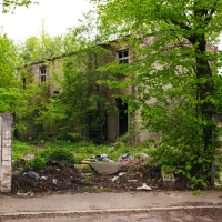 A building in Iļģuciems surrounded by woods and featuring a gate.