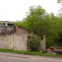 A Iļģuciems brick building with a tree in front of it.