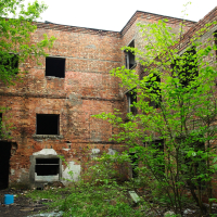 A broken-windowed brick building in Iļģuciems.