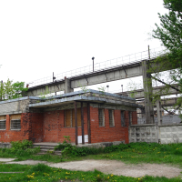 A brick building in Iļģuciems next to a bridge.