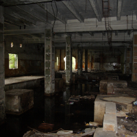 A Iļģuciems room with a dirty floor and a puddle of water.