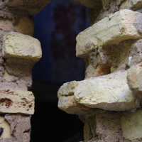 A Iļģuciems brick wall with a hole in it.