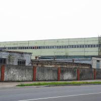 A large building in Iļģuciems with a fence in front of it.