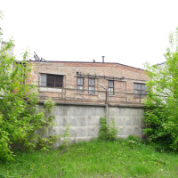 An old Iļģuciems building next to a grassy area.