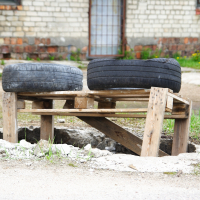 Two tires sitting on top of a wooden bench in Iļģuciems.