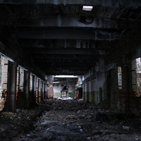 An eerie, dilapidated interior of Karosta's abandoned building, showcasing crumbling brick walls, scattered debris, and a desolate hallway leading into darkness, under the remnants of a once-sturdy concrete