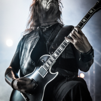 A musician with long hair and face paint, donning a black sleeveless leather vest, passionately plays an electric guitar on stage during the 2015 Kilkim Žaibu festival. The background is misty with stage lights creating an atmospheric effect. The photo is watermarked with "xltphoto.net" in the bottom right corner.