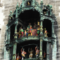 An ornate clock tower in Munich with a mechanical performance, featuring vividly colored figures akin to royalty and jesters, set against a gothic-style architectural backdrop.