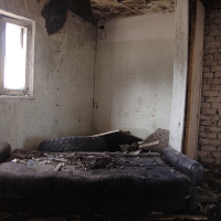 A Skulte couch in a room with a broken window.