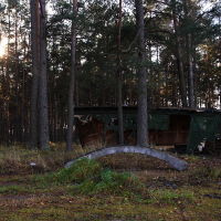 The sun is shining on a Skulte building in the middle of a wooded area.