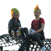 Two children with bright green and orange mohawk hairstyles sit atop a metal structure. Each child holds a bottle with beverage, and both have serious expressions. The child on the left wears a black leather jacket, while the one on the right sports a red and black outfit, capturing the essence of punk at Laulupidu.