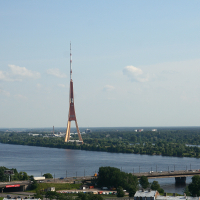 A bridge over a river with a tall tower in Riga from above.