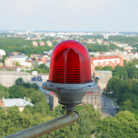 A red light on top of a pole seen from Riga.