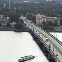 A boat is crossing a bridge over a body of water in Riga from above.