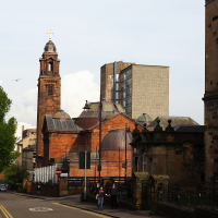 A sunny day captures the architectural contrast between the ornate historic buildings in Scotland destinations and the modern high-rise structure in the background, while pedestrians stroll along the street.