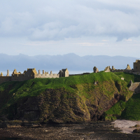 A majestic, ancient castle rests atop verdant coastal cliffs in Scotland, partially in ruins, under a dramatic sky, illustrating a rich historical narrative amidst natural beauty.