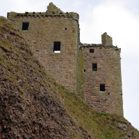 Ancient stone castle ruins perched precariously on a rugged cliff in Scotland, weathered by time and elements, standing as a silent sentinel to history.