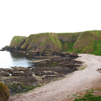 A serene rocky beach curves beside lush green cliff faces in Scotland, met by calm waters, under a hazy sky, showcasing a tranquil coastal landscape.
