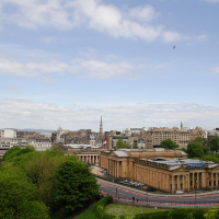 A panoramic view of a cityscape featuring historical architecture, lush greenery, and a clear sky with a solitary bird in flight embodies the fusion of urban life and natural beauty, capturing the essence of Scotland
