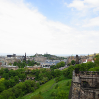 A panoramic view of Edinburgh with its historic architecture, green spaces, and the Firth of Forth in the distance, captured from an elevated vantage point near Edinburgh Castle. This iconic scene highlights the