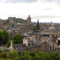 A scenic view of Edinburgh's historic skyline, showcasing medieval and neoclassical buildings against a backdrop of greenery, with the Edinburgh Castle prominently perched on its rocky hill, encapsulates the rich
