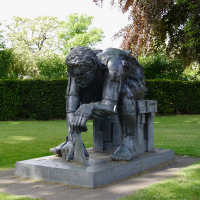 A somber bronze sculpture of a seated, headless figure in a contemplative pose, surrounded by lush greenery in Scotland, inviting reflection amidst nature.