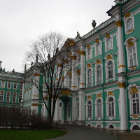An ornate, green and white baroque facade with gilded embellishments under a cloudy sky, characteristic of historic St. Petersburg architecture, likely a section of a palace or government building.