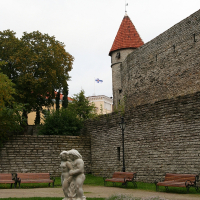 A Tallinn wall with a statue in front of it.