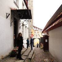 In Tallinn, a woman stands on a cobblestone street.