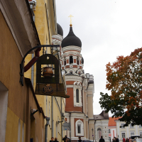 People walking down a cobblestone street in Tallinn near a church.