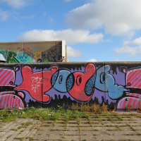 A Tallinn wall adorned with graffiti under a blue sky.
