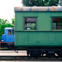 Two green train cars parked next to each other at a train museum.